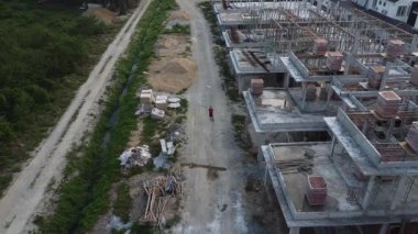 Hala yapım aşamasında olan boş arazinin etrafında insansız hava aracı uçuran bir adamın hava görüntüleri..  