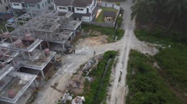 Hala yapım aşamasında olan boş arazinin etrafında insansız hava aracı uçuran bir adamın hava görüntüleri..  