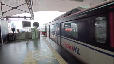 Kuala Lumpur, Malezya. Temmuz 01.2025: KLCC orta kapasiteli hafif hızlı geçiş (LRT) demiryolu istasyonu sahnesi Kuala Lumpur kentsel manzarası boyunca geliyor ve çıkıyor.