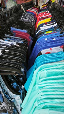 Perak, Malezya. 10 Temmuz 2025: Kg Koh perşembe pazarında indirimde ve sergilenmekte olan askılarda rengarenk giysiler bulunan güzel düzenlenmiş bir elbise rafı.