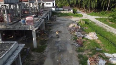 İkametgah evlerinin yakınındaki boş arazide insansız hava aracı uçuran bir adamın hava görüntüleri..