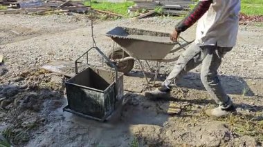 Perak, Malezya. 25 Temmuz 2025: Beton karıştırıcı üzerinde çalışan işçi, tramvayda çimento taşıyor, daha sonra kare şeklindeki metal kovayla halata döküyor ve Taman Permai Konut projesinde beton kaldırıyor, Kg Koh.