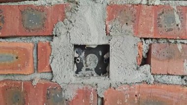 Yeni elektrik soketi deliği tuğla beton duvara monte ediliyor. 