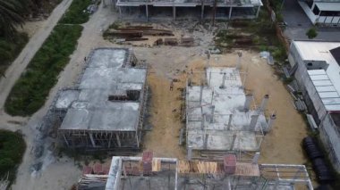 İkametgah evlerinin etrafında uçan bir erkek modelin havadan çekilmiş görüntüleri. İnşaat halindeki küçük boş arazisi var.. 