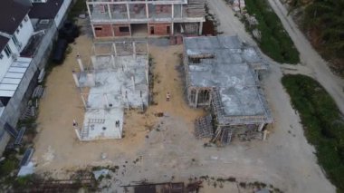 İkametgah evlerinin etrafında uçan bir erkek modelin havadan çekilmiş görüntüleri. İnşaat halindeki küçük boş arazisi var.. 