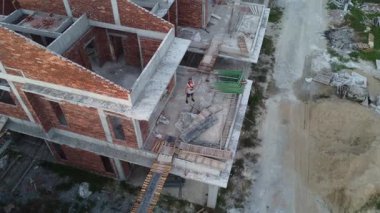 İkametgah evlerinin etrafında uçan bir erkek modelin havadan çekilmiş görüntüleri. İnşaat halindeki küçük boş arazisi var.. 