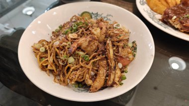 Bir tabak kızarmış sarı şehriye, yanında kızarmış patates ve karides.. 