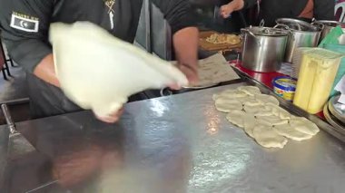 Perak, Malezya. 17 Ağustos 2025: Malezyalı bir sokak yemeği şefi, Roti Canai Sedap standında tavada ekmek pişirme konusundaki uzmanlığını gösteriyor, Kg Koh. 