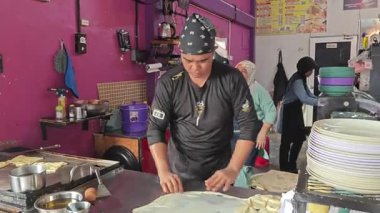 Perak, Malezya. 17 Ağustos 2025: Malezyalı bir sokak yemeği şefi, Roti Canai Sedap standında tavada ekmek pişirme konusundaki uzmanlığını gösteriyor, Kg Koh. 