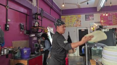 Perak, Malezya. 17 Ağustos 2025: Malezyalı bir sokak yemeği şefi, Roti Canai Sedap standında tavada ekmek pişirme konusundaki uzmanlığını gösteriyor, Kg Koh. 