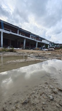 Bitmemiş inşaat binasının etrafında toplanan durgun yağmur suyu havuzu.