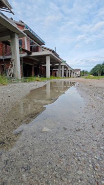 Bitmemiş inşaat binasının etrafında toplanan durgun yağmur suyu havuzu.