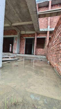 Bitmemiş inşaat binasının etrafında toplanan durgun yağmur suyu havuzu.