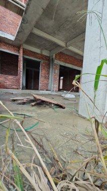 Bitmemiş inşaat binasının etrafında toplanan durgun yağmur suyu havuzu.