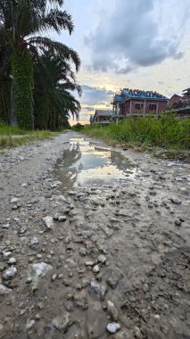 Kırsal toprak yolda sağanak yağış sonrasında durgun su havuzu yansıtıyor. 