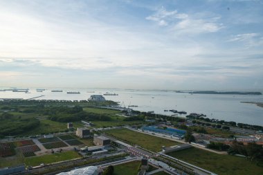 Singapur 'daki yat limanı bölgesinin yanında limana varmak için bekleyen gemiler var.