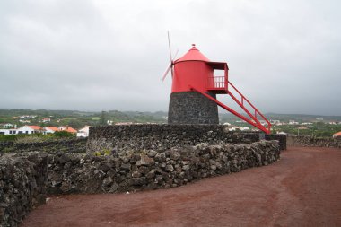 Volkanik taş duvarlı kırmızı yel değirmeni. Pico adasındaki şarap depoları.