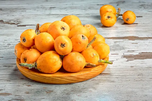 Köy masasındaki ahşap kasede taze loquats.