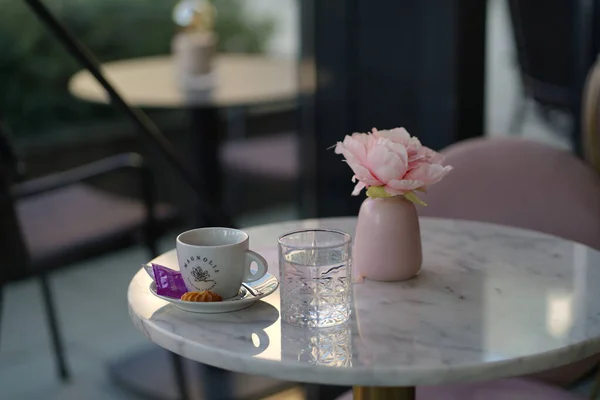 A cup of coffee and the flower on the table in the cafe in spring. Cute table in the morning coffee house. Pretty rest space in the restaurant