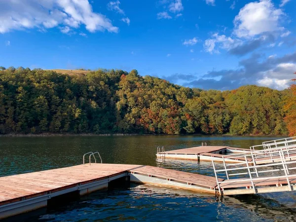 Wooden pontoon on a lake surrounded by forest turning yellow on a sunny autumn day with clear blue sky