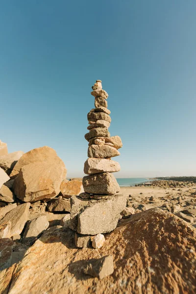 stock image Pyramid of sea pebbles on a sunny rocky beach. Life balance and harmony concept, vertical banner