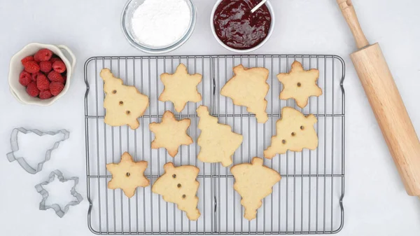 Christmas shortbread cookies with raspberry jam recipe, close up baking process, flat lay. Baked cookies close up on cooling rack