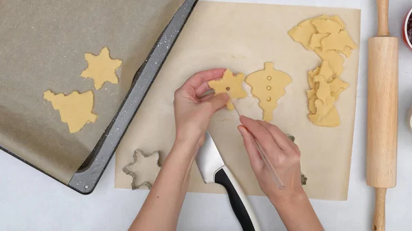 Christmas shortbread cookies with raspberry jam recipe, close up baking process, flat lay. Chef making holes in cookie center using a straw