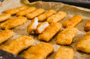 Vahşilikten yapılmış çıtır çıtır balık çubukları, Alaska Pollock 'u fırından yeni çıkmış bir tavaya yakın plan çekerken yakalamış.