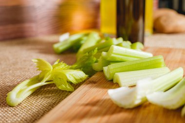 Kereviz çorbası tarifi. Çiğ yeşil kereviz çubukları mutfak masasındaki ahşap kesme tahtasına yakın plan.