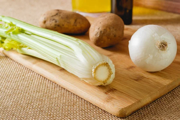 Köy arka planında tahta kesim tahtasındaki çiğ sebzeler. Kereviz çorbası tarifi için gerekli malzemeler