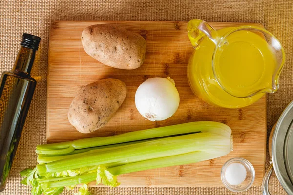 Kereviz çorbası tarifi. Çiğ sebzeler, örneğin kereviz sapı, patates, soğan, zeytinyağı, ve mutfak masasının üzerine yakın plan et suyu.