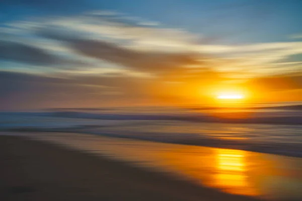Abstract seascape. Tranquil scene of empty sand beach at sunset. Golden waves, sun reflections, motion blur, copy space for the text