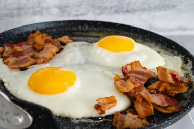 Kızarmış yumurta ve kızarmış domuz pastırması kızartma tavasında yakın plan. İngiliz kahvaltısı