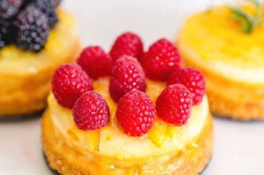 Böğürtlenli cheesecake ve turuncu jöle yakın plan. Farklı soslu mini peynirli kekler.