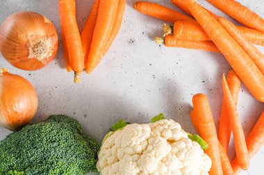 Carrots, cauliflower, broccoli, onions close-up on a light grey background, flat lay with copy space