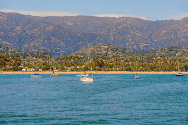 Santa Barbara harbor, California. Boat on a water, beautiful beach with palm trees, and mountains on a horizon