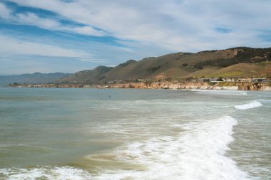 Beautiful Pacific Ocean, green cliffs, and cloudy sky. Pismo Beach, California Central Coast