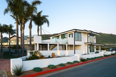 Beautiful houses with ocean views, with nicely landscaped front the yard in a small beach town somewhere in California at sunset