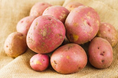 Red potatoes close-up. Fresh raw organic red potatoes close-up on a rustic background on a kitchen table