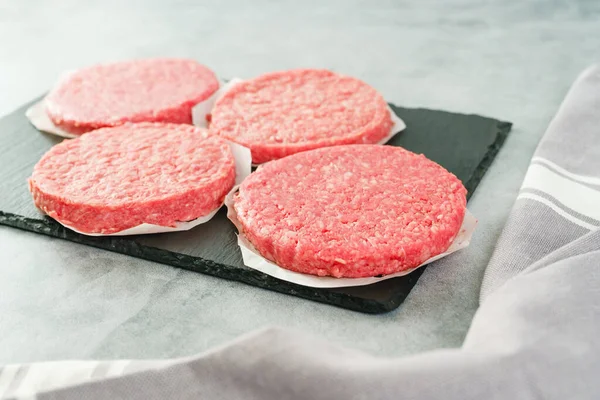Burger patties close-up. Fresh raw burger patties close-up on a grey stone background, copy space