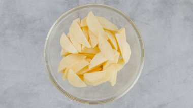 Sliced apples in a glass bowl close-up on a kitchen table, flat lay with copy space