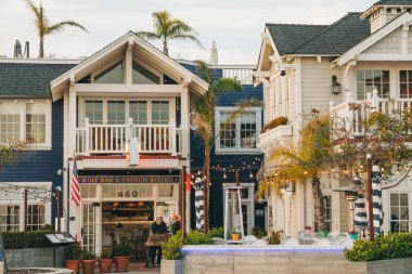 Avila Beach, California, USA - February 2, 2023.  Avila Beach city promenade filled with restaurants, shops, patios, benches, and art. Sunset in the city, dinner time