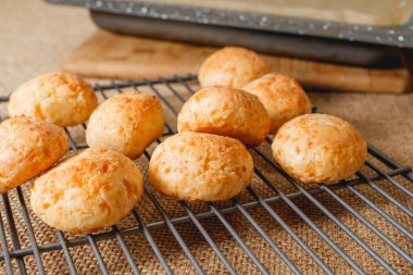 Taze pişirilmiş geleneksel Brezilya peynirli ekmek topları mutfak masasındaki soğutma rafına yakın plan.