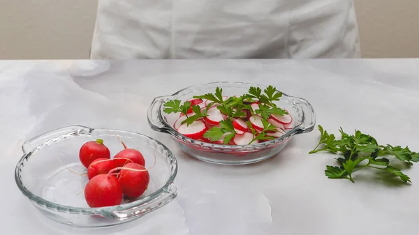 新鲜的切碎萝卜 新鲜的绿色欧芹紧密地贴在淡灰色背景的玻璃板上 供应蔬菜沙拉的妇女 — 图库照片