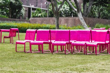 Şehir parkında yeşil çimenlikte modern metal renkli sandalyeler, şehir ortamında dinlenmek için rahat..