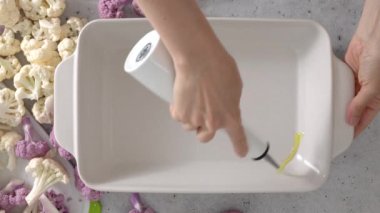 Şef beyaz seramik fırın tepsisine zeytinyağı döktü. Fırında kızartılmış karnabahar tarifi..