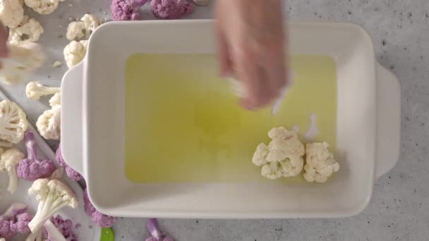 薄い灰色の石の背景にオリーブオイルのクローズアップで霧雨の白いセラミックベーキングパン オーブンローストカリフラワーの小花のレシピ — ストック動画