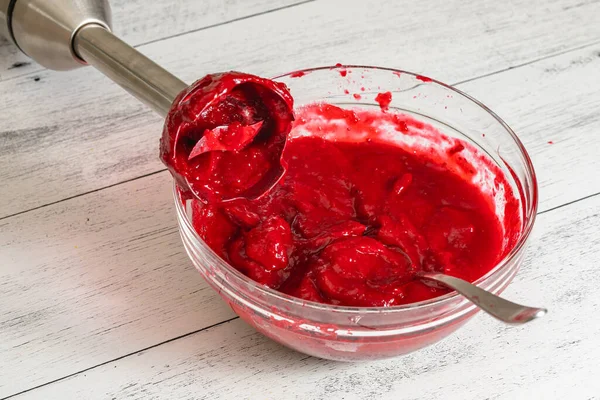 Blending cranberry sauce, making it extra-smooth. Bowl of fresh cooked homemade cranberry sauce close-up on kitchen table