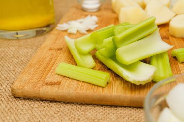 Çiğ sebzeler, mesela kereviz çubukları, patates, mutfak masasında doğranmış soğan. Kereviz çorbası tarifi için gerekli malzemeler