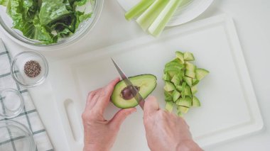 Avokado çukurunu temizleyen kadın. Yeşil salata, kereviz, marul ve avokado tarifi. Beyaz arkaplan üzerindeki içerikler
